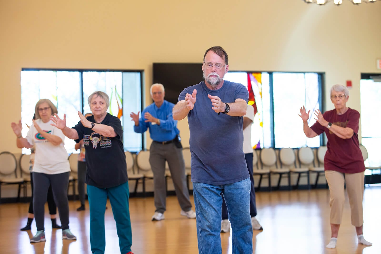 Man leads a tai chi at senior center. many participants