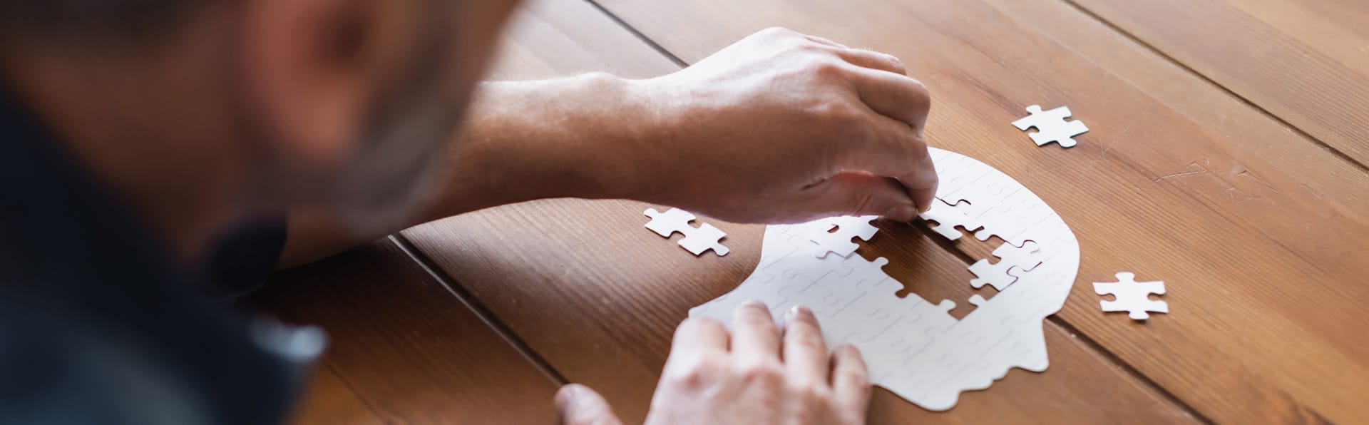 GUIDE program, Man putting together pieces of puzzle. Puzzle forms a human head. Dementia programs