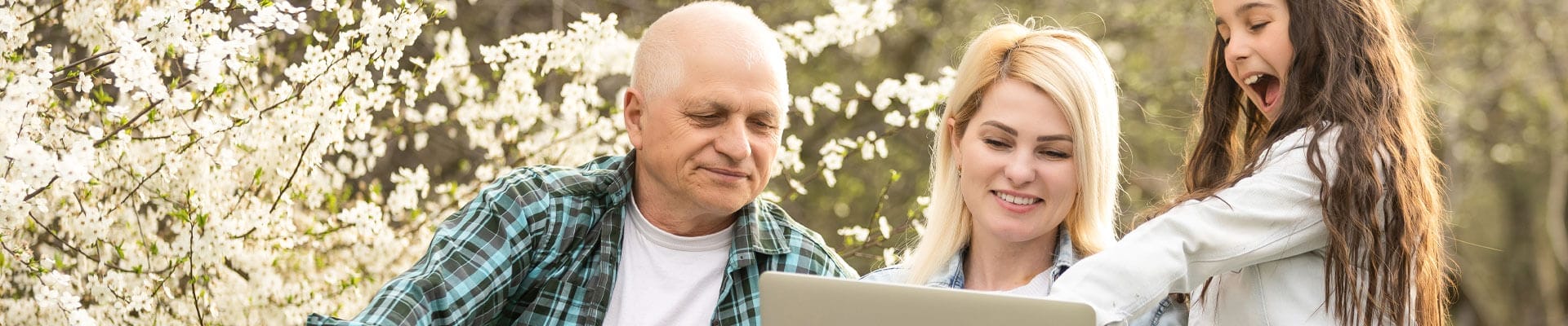 Elderly man explains how to use a laptop to his granddaughter.